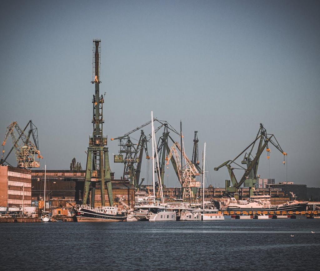 View of the bustling industrial port at Gdańsk Shipyard with cranes, ships, and dock facilities.